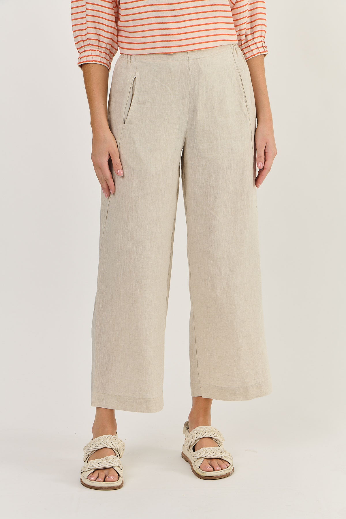 Person wearing beige wide-leg pants and a striped shirt on a plain background
