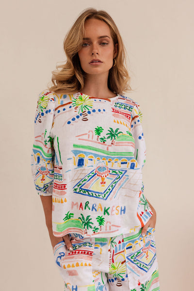 Woman wearing a colorful 'Marrakesh' dress with a pattern of a square and palm trees.