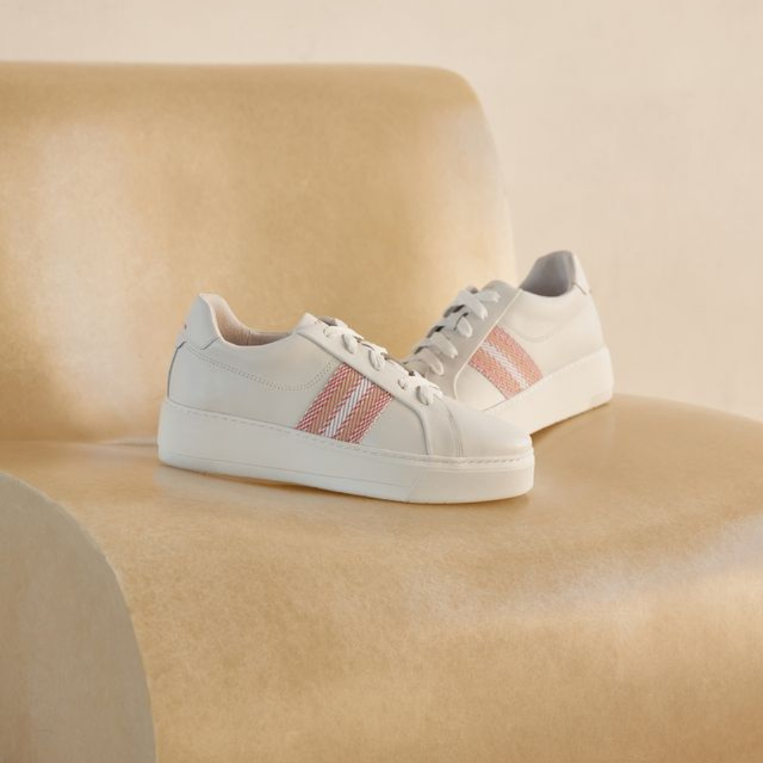 White sneakers with pink stripes on a beige chair