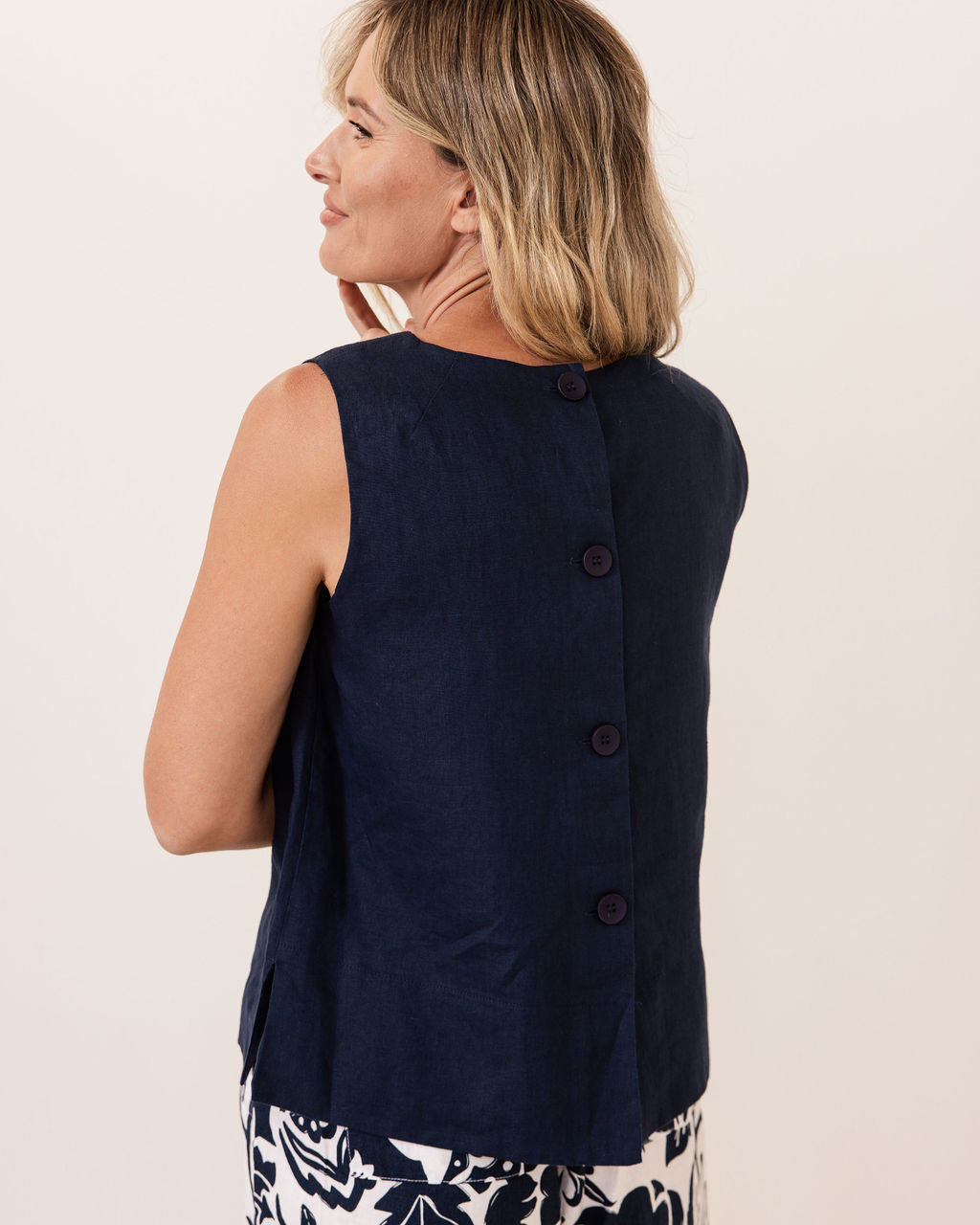 Woman wearing a navy sleeveless blazer on a light background
