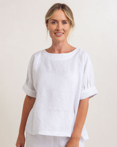 Woman wearing a white blouse against a plain background