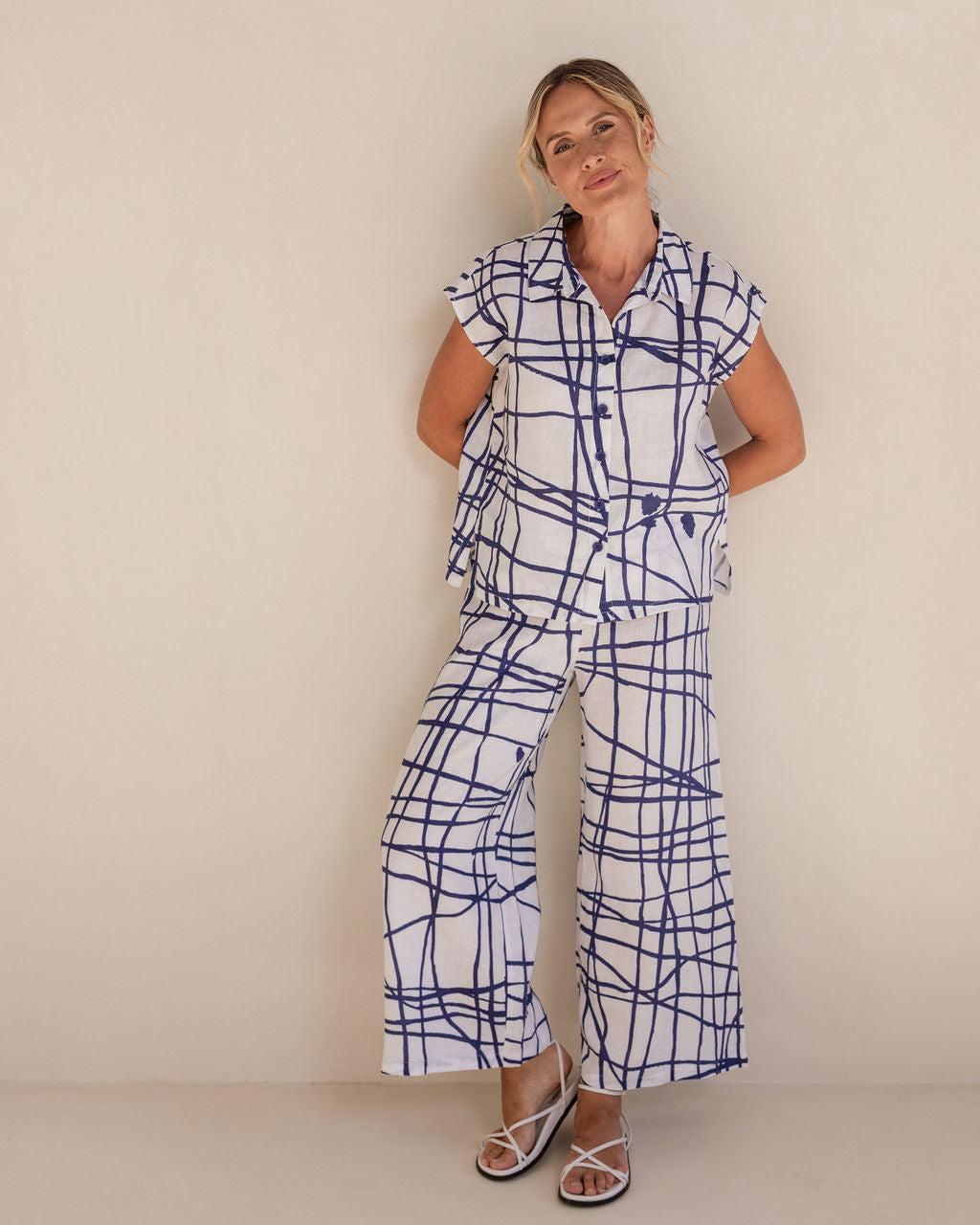 Woman wearing a blue and white patterned outfit against a plain background