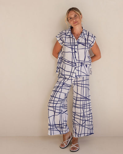 Woman wearing a blue and white patterned outfit against a plain background