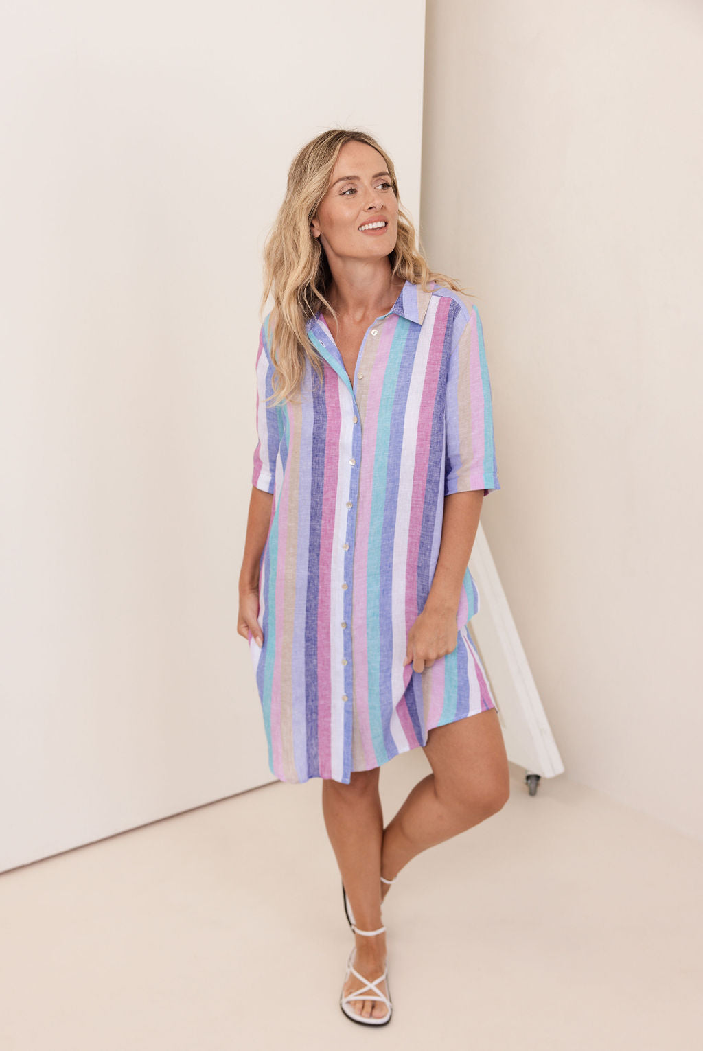 Woman wearing a pastel striped shirt dress against a white background