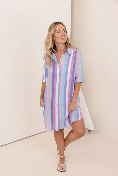Woman wearing a pastel striped shirt dress against a white background