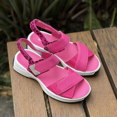 Pink sandals with white soles on a wooden surface