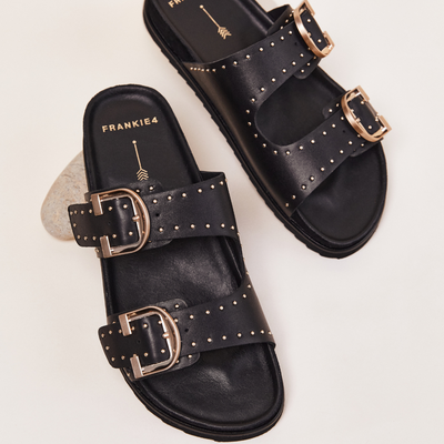Black sandals with gold buckles on a light background