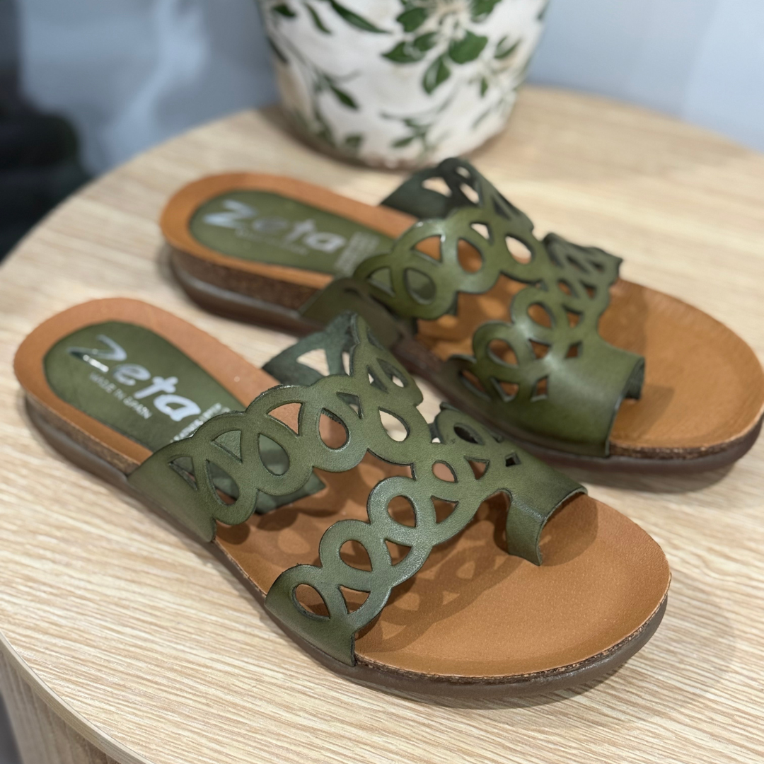 Green sandals with brown soles on a wooden surface, featuring the brand 'Zeta'.