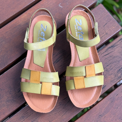 Pair of colorful sandals with 'Zeta' branding on a wooden surface