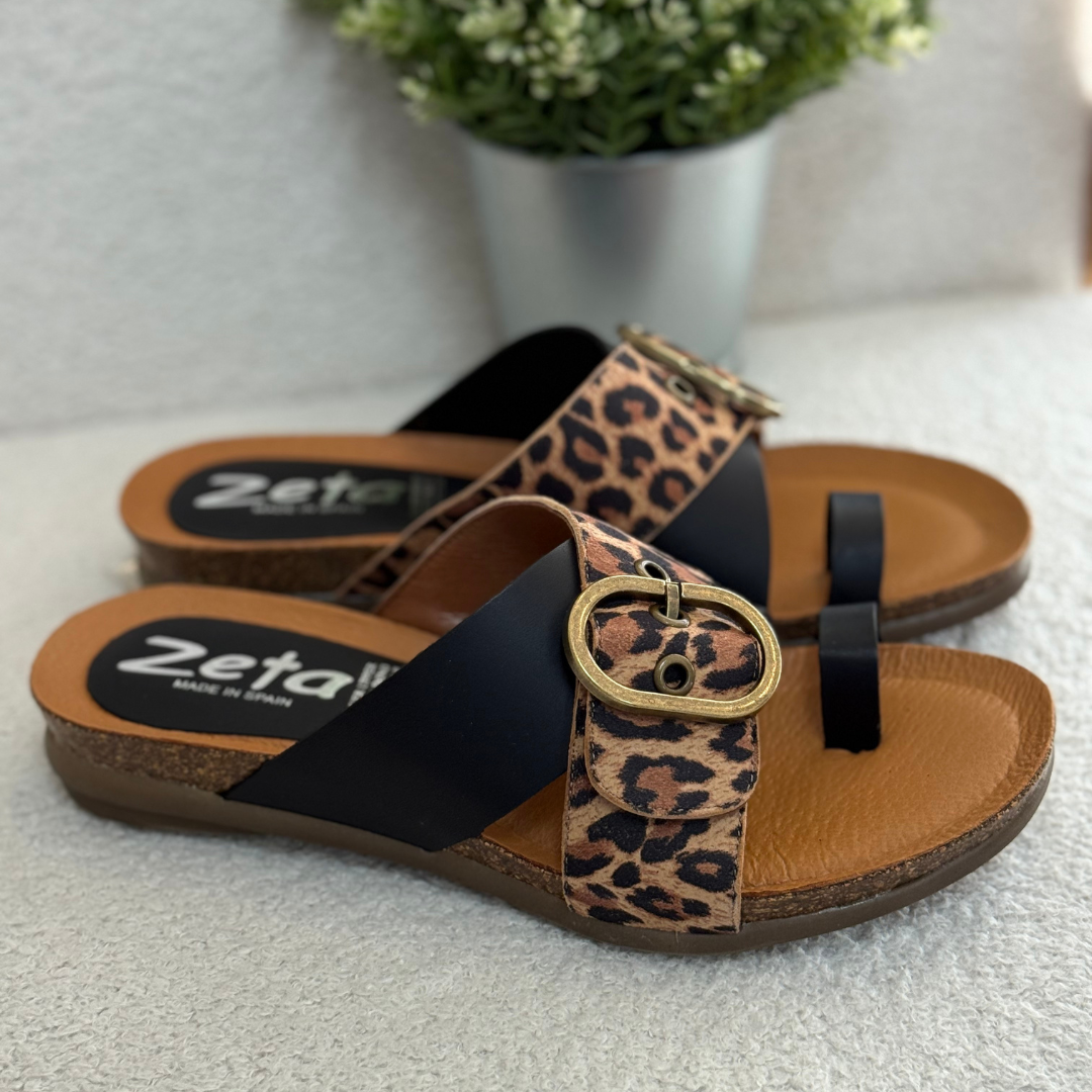 Pair of sandals with leopard print strap on a light surface