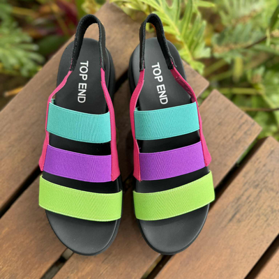 Colorful sandals with striped straps on a wooden surface