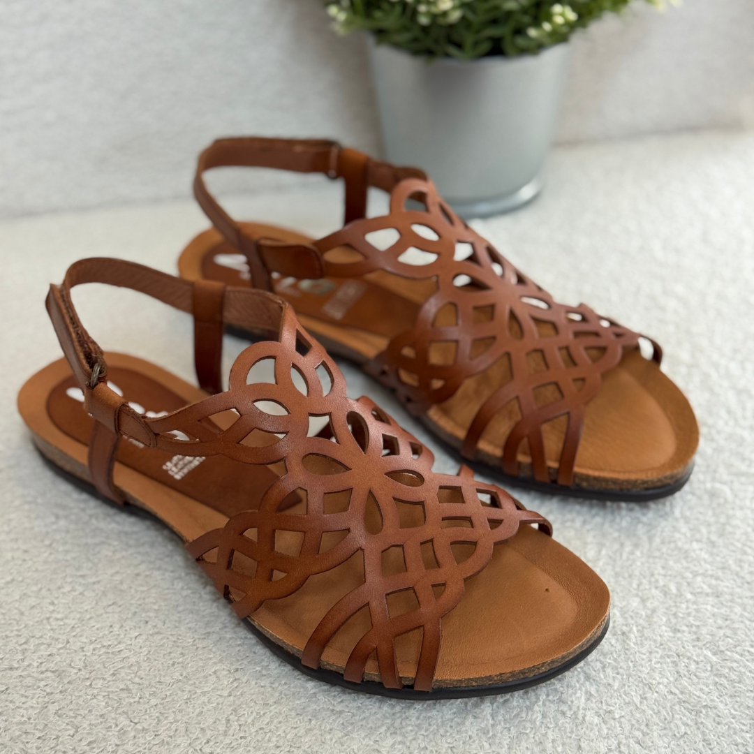 Pair of brown sandals with intricate designs on a light surface.