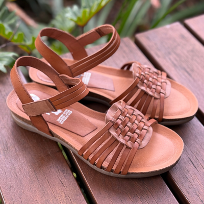 Tan sandals with woven straps on a wooden surface