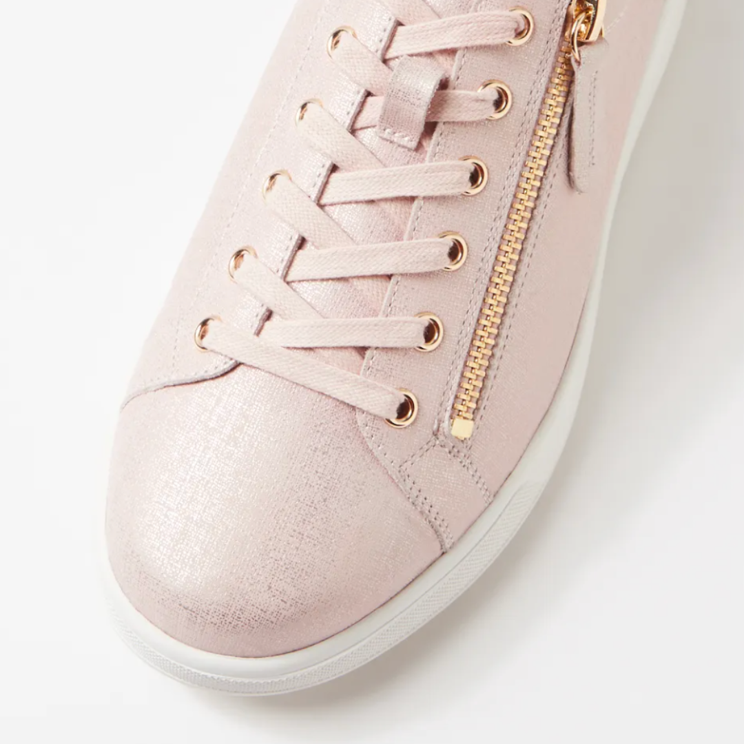 Pink sneaker with gold laces and zipper on a light background