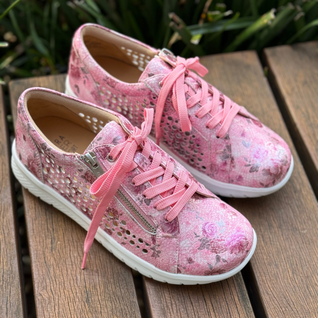 Pink floral sneakers with pink laces on a wooden surface